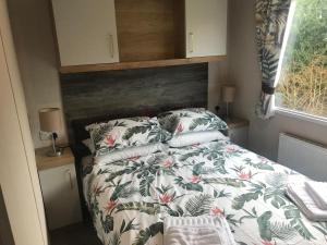 a small bedroom with a bed with a floral comforter at Flamingo Land Private Caravan - No 8 Cedarwood in Kirby Misperton
