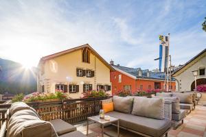 eine Terrasse mit Sofas und Tischen auf einem Gebäude in der Unterkunft Hotel Engadinerhof Superior in Pontresina