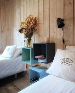 ein Schlafzimmer mit 2 Betten und einem Nachttisch mit einer Blumenvase in der Unterkunft Kwitnące Jabłonie. Całoroczne Domki Wypoczynkowe in Obrazów