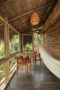 una stanza con amaca in un resort con tavolo e sedie di Yaxchen Tulum Cabañas & Cenote a Tulum