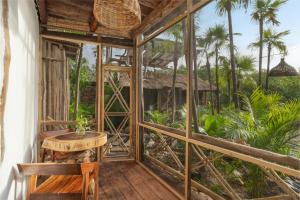 Habitación con mesa, sillas y árboles en Yaxchen Tulum Cabañas & Cenote en Tulum