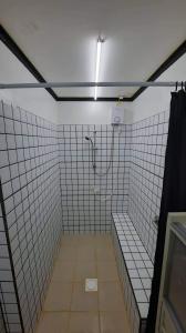 a bathroom with a shower and a tiled wall at Pretty flat with full AC 
