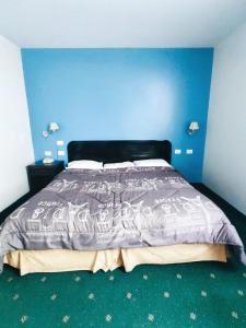 1 dormitorio con 1 cama con pared azul en Venecia Hotel Carrion, en Trujillo