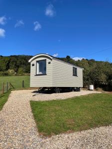 a small white trailer sitting on top of a field at The Shepherd’s Nest in Bristol