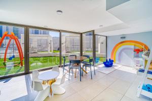 Una habitación con una mesa y sillas y un parque infantil. en Galerna Home 2BR W/Balcony, Wifi & Parking., en Concón