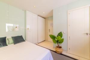 una camera con un letto bianco e una pianta in vaso di AmazINN Places Gran Via III a Madrid