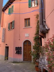 a pink building with a wooden door and a building at Confortevole casa di montagna- La Campana in San Marcello Pistoiese