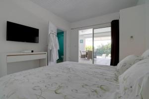 a white bedroom with a large bed and a flat screen tv at Villa the Lodge - Lagon Saint-François in Saint-François +35 photos