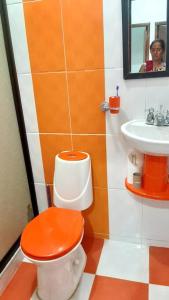 baño con aseo con tapa naranja y lavamanos en Casa comoda con excelente ubicacion, en Mariquita