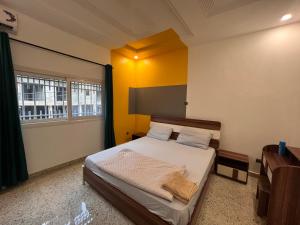 sypialnia z łóżkiem z żółtymi ścianami i oknem w obiekcie SMB-gn RÉSIDENCE LAMBANDJI w mieście Konakry