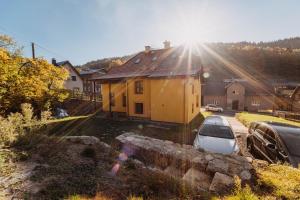 a car parked in front of a yellow house at Holiday house Vedle in Desná