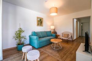 ein Wohnzimmer mit einem blauen Sofa und einem TV in der Unterkunft 188 Apartments - Lantana - pool, garden and patio in Cascais