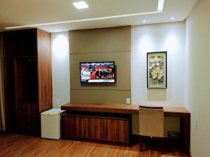 una oficina con escritorio y TV en la pared en Hotel Panorâmico, en Carmo do Paranaíba