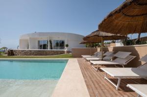 una piscina con sillas y sombrillas junto a una casa en Villa Escargot Luxury in Costa Rei Beach en Costa Rei