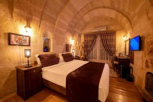 um quarto com uma cama grande num quarto de pedra em Portal Cappadocia Hotel em Ortahisar