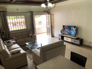 uma sala de estar com um sofá e uma televisão em Grand Appartement à essos mobile em Iaundé