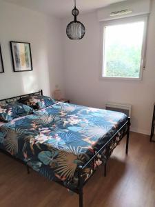 um quarto com uma cama com um edredão colorido e uma janela em Petit chemin des Flouries em Gaillac