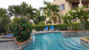 a pool in front of a house with blue chairs and flowers at Placencia Pointe Townhomes #7 in Placencia Village