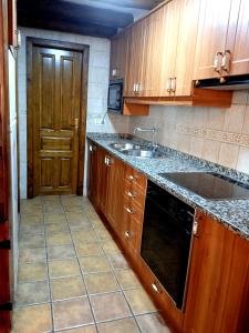 a kitchen with wooden cabinets and a sink and a door at Casa La Tornagua in Biescas +7 photos