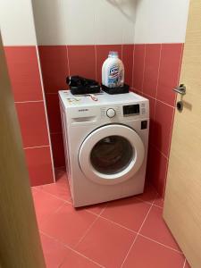 a washing machine in a bathroom with a red wall at MB luxury apartments in Tirana