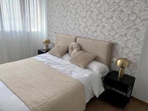 sypialnia z białym łóżkiem i tapetą w kwiaty w obiekcie Don Gustavo Modern Apartment, Sea Views & Pool w mieście Benalmádena