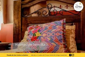a bed with a wooden head board with a pillow at Posada de San Carlos La Quinta in Antigua Guatemala