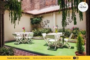 two tables and chairs on a patio with plants at Posada de San Carlos La Quinta in Antigua Guatemala