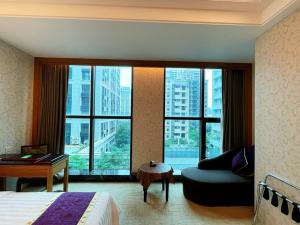 a hotel room with a bed and a couch and windows at Happiness Inn Hotel in Xinzhuang