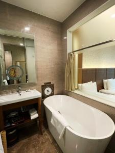 a bathroom with a tub and a sink and a bed at Happiness Inn Hotel in Xinzhuang