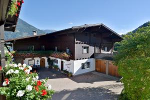 a house with a fence and flowers in front of it at Riemenerhof in Fügen