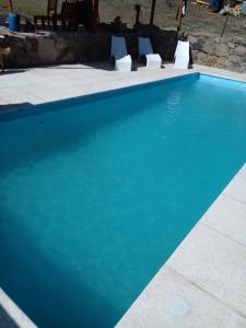 una piscina azul con 2 sillas blancas al lado en Cabañas "La Quimera" en El Durazno