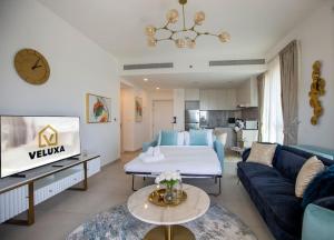 Veluxa - Luxury and bright 1 bedroom apartment, Burj view! في دبي: غرفة معيشة مع أريكة زرقاء وسرير