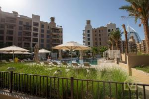 une piscine avec des parasols, des tables, des chaises et des bâtiments dans l'établissement Veluxa - Luxury and bright 1 bedroom apartment, Burj view!, à Dubaï