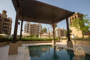 a pavilion with a swimming pool in a city at Veluxa - Luxury and bright 1 bedroom apartment, Burj view! in Dubai