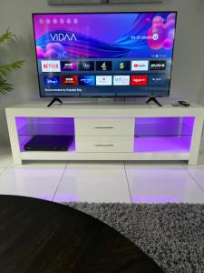 a television on a white entertainment center with purple lights at Belle Luxury Apartments in Gros Islet