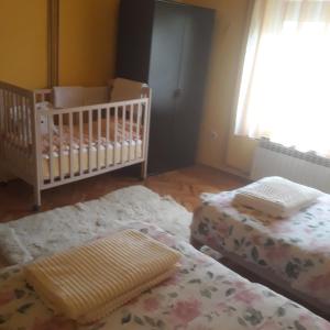 a room with two beds and a crib and a baby crib at Apartman "Dom Stankovića" in Pirot