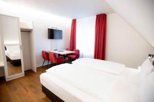 a hotel room with two beds and a table at Reos Hotel Wangen in Wangen im Allgäu