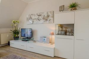 a living room with a white cabinet with a computer on it at Westbrise App 7 in Wenningstedt