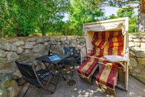 a bed and a table and chairs next to a stone wall at App Reetlodge in Keitum