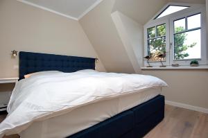 una camera da letto con letto con testiera blu e finestra di Syltmuschel a Westerland