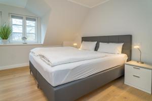 ein Schlafzimmer mit einem großen Bett mit weißer Bettwäsche in der Unterkunft Sylt Oase in Westerland