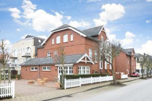 a large red brick building with a white fence at App Wellness in Westerland (Sylt)