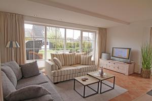 a living room with a couch and a tv at Friesenjung in Wenningstedt