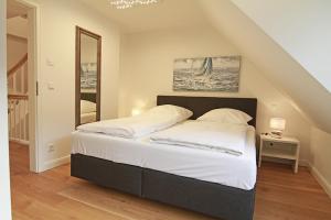 a bedroom with a large bed with white sheets at Gode Stuv in Westerland