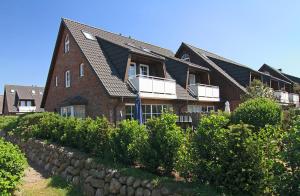 a large brick house with a stone wall at Friesenjung in Wenningstedt