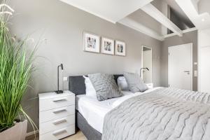a white bedroom with a large bed and plants at Anker Hus in Westerland