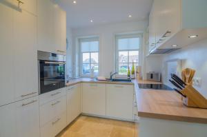 a large white kitchen with white cabinets and windows at Hoogen Hüs in Westerland