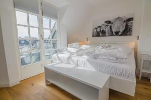 a white bedroom with a bed and a window at Hoogen Hüs in Westerland