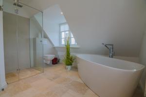 a bathroom with a large white tub and a toilet at Hoogen Hüs in Westerland +9 photos