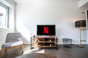 un soggiorno con TV e sedia di G59 LOFTS l Zona Stazione Centro l Netflix & Wi-Fi Fibra l a Parma
